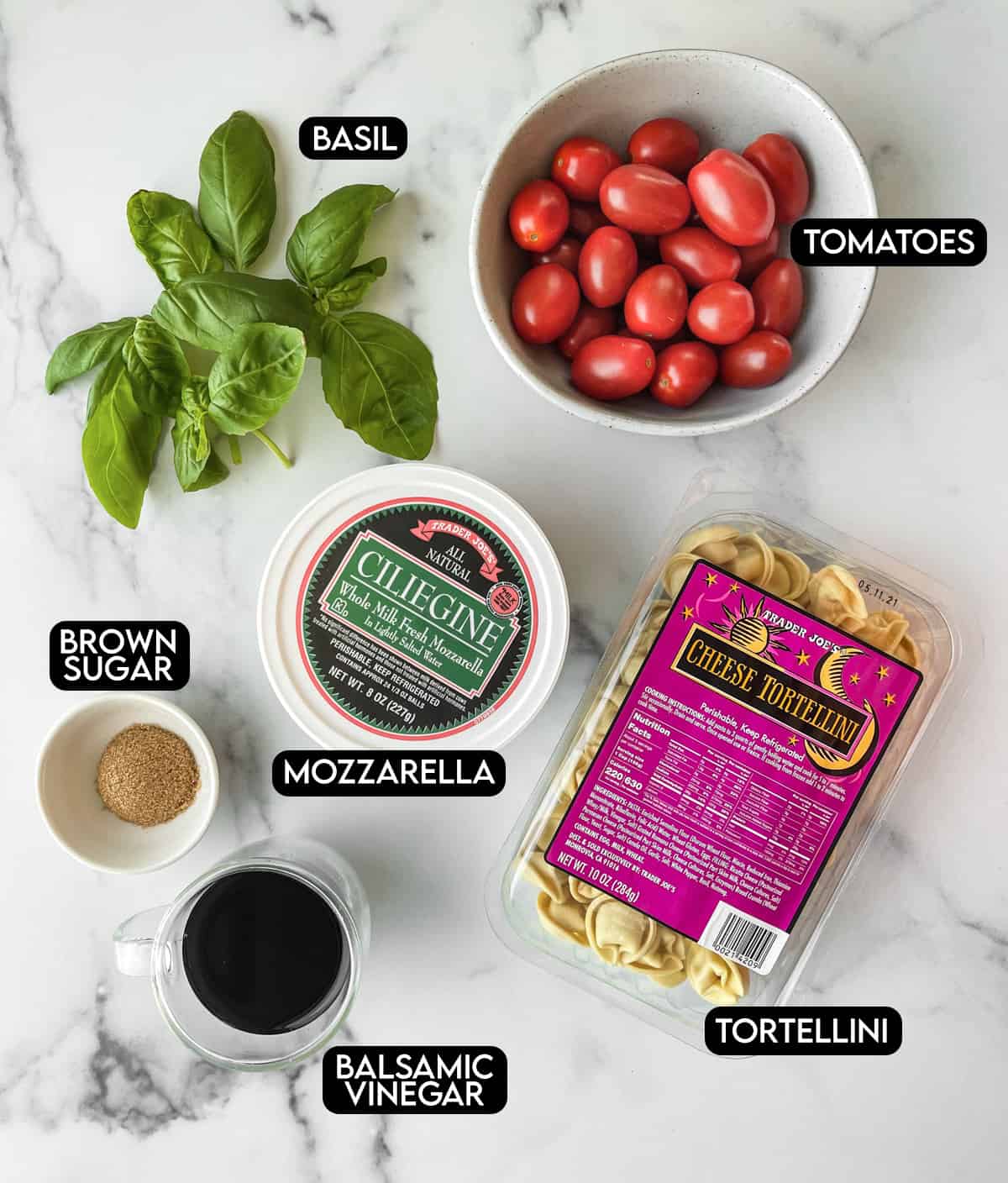 Labeled ingredients for tortellini caprese: basil, tomatoes, brown sugar, mozzarella, balsamic vinegar, and tortellini.