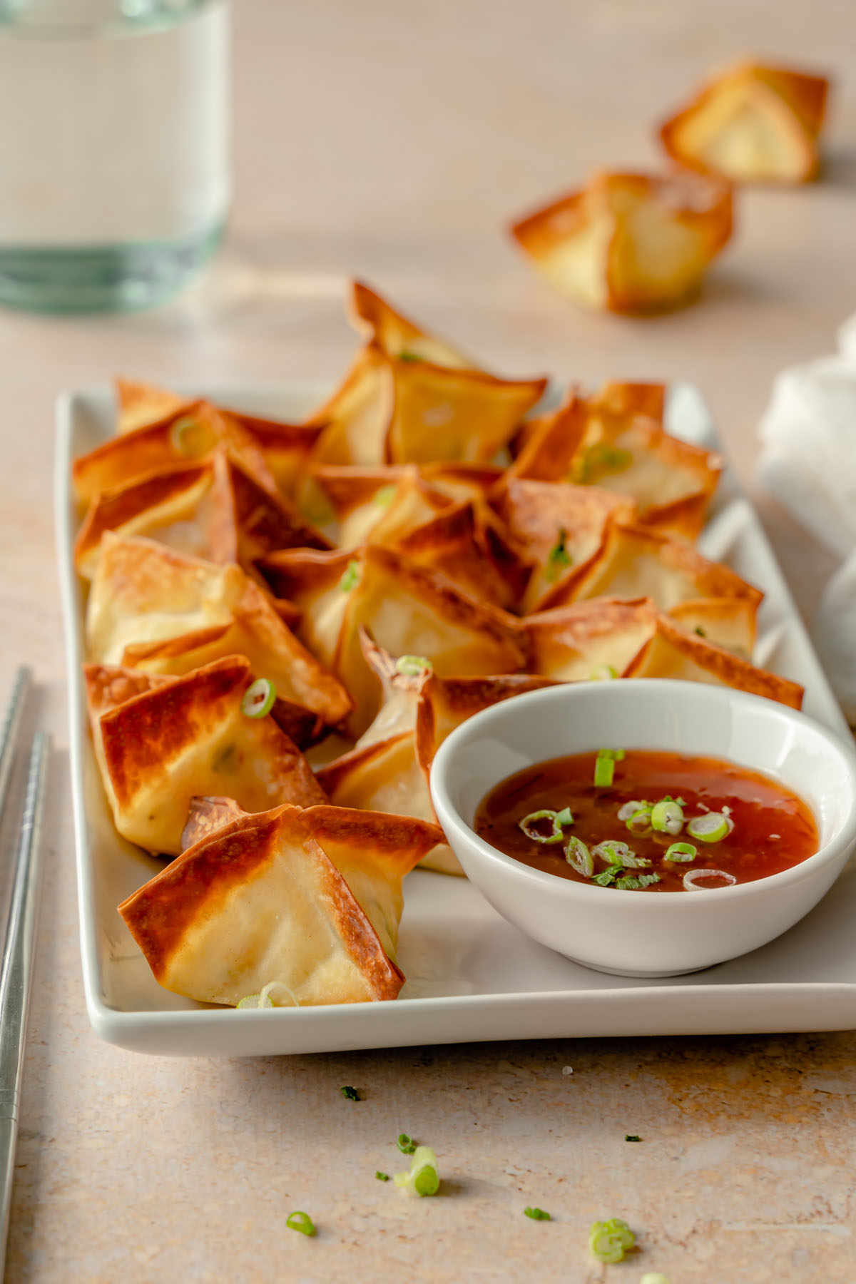 Platter of Air Fryer Crab Rangoons with dipping sauce and chopsticks to the side.