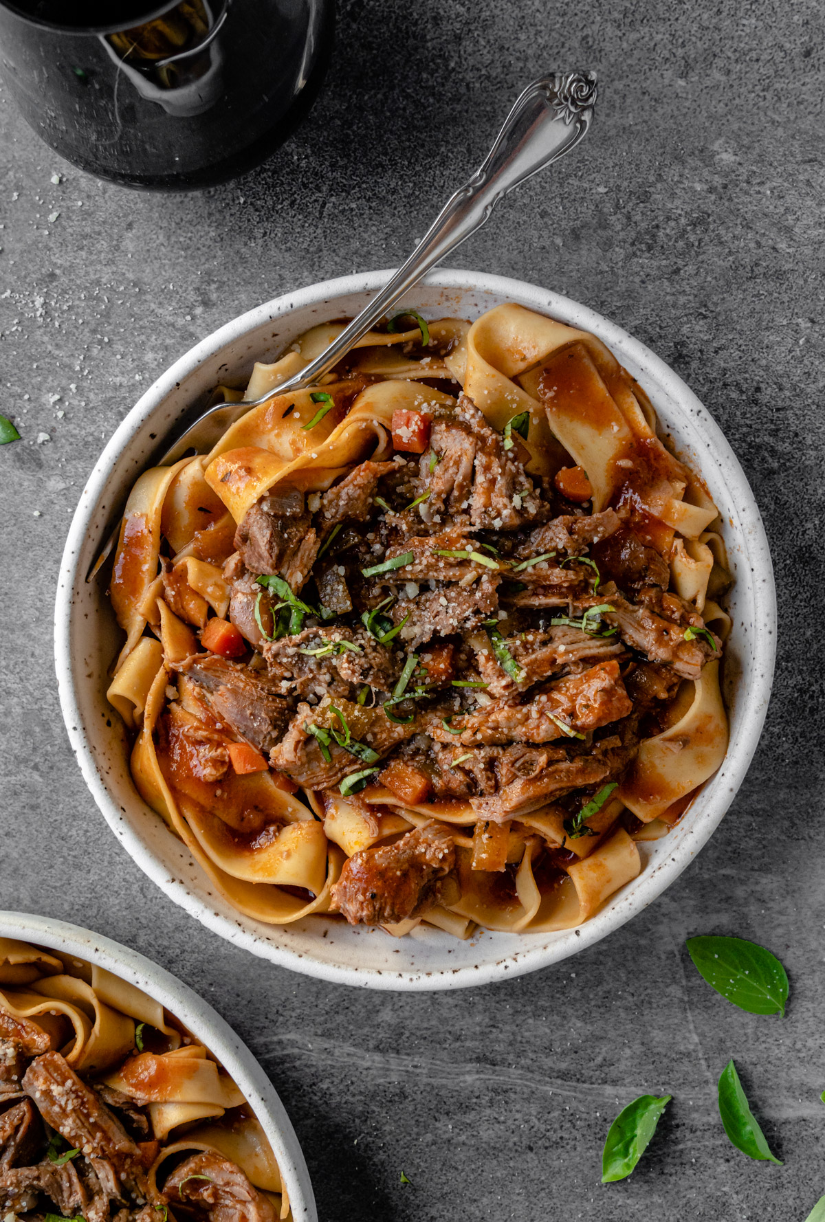 Bowl of pappardelle pork ragu with fork and glass of wine