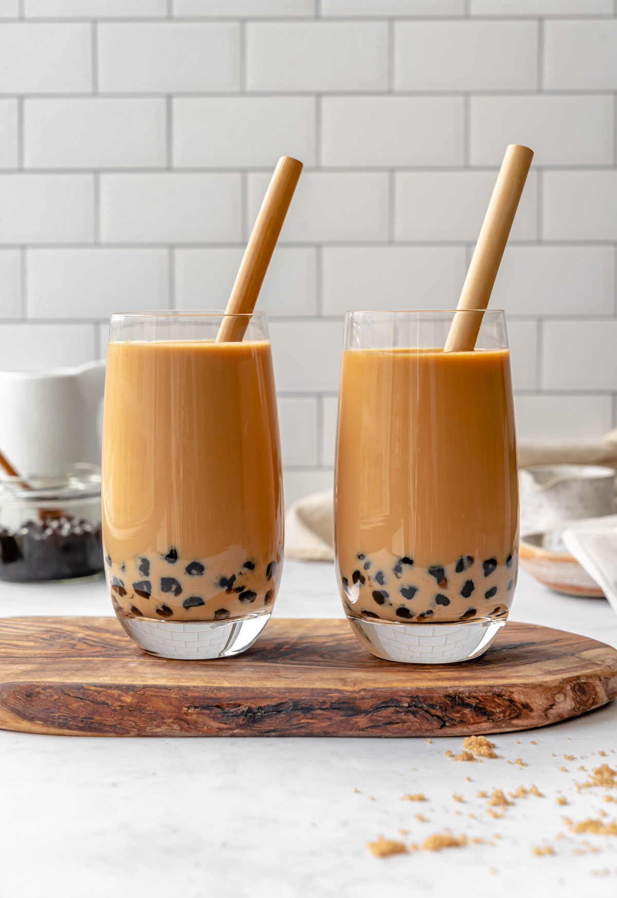 Two glasses of milk tea boba with straws on a serving tray.