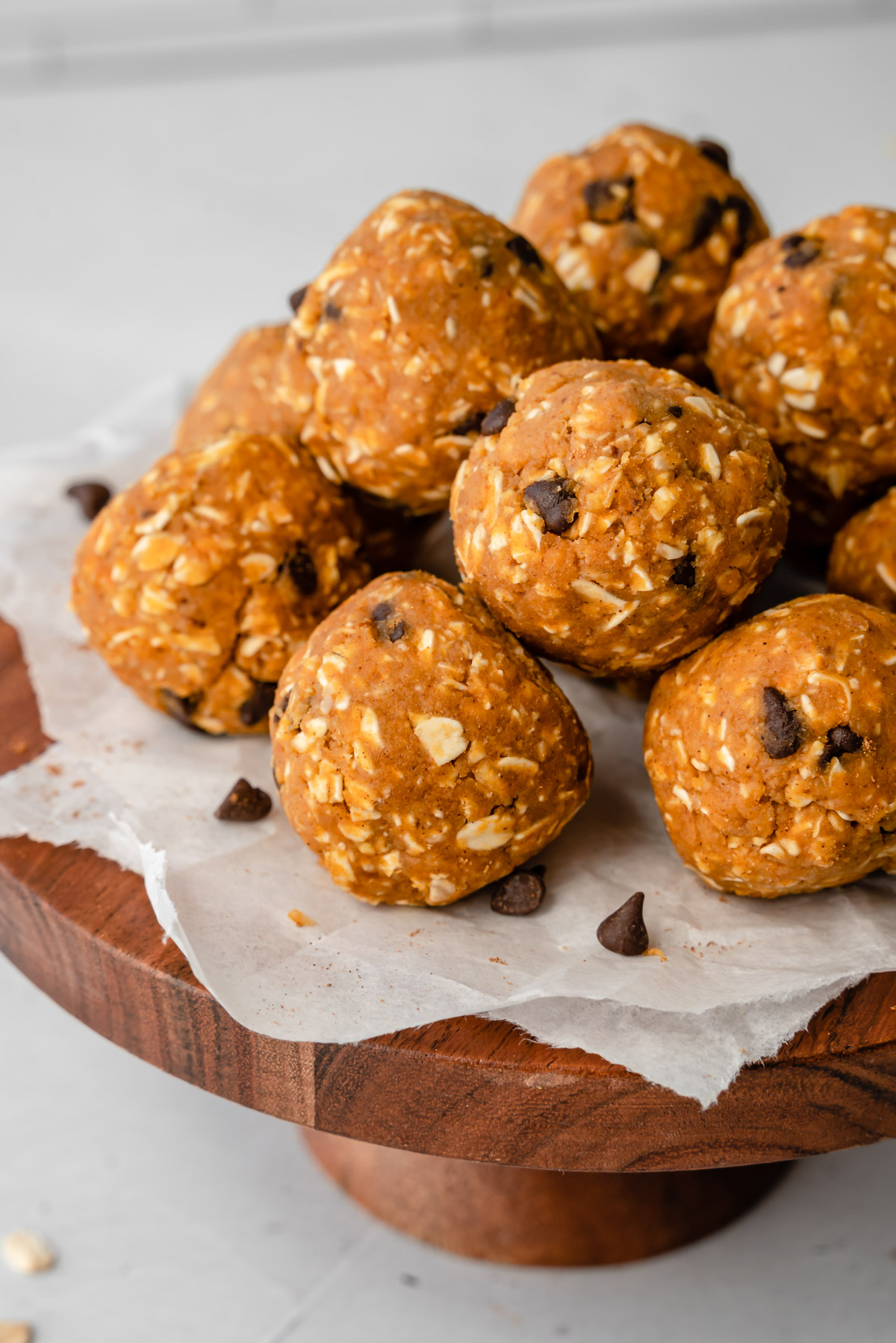 Close up of pumpkin energy balls on parchment paper on wooden cake stand.