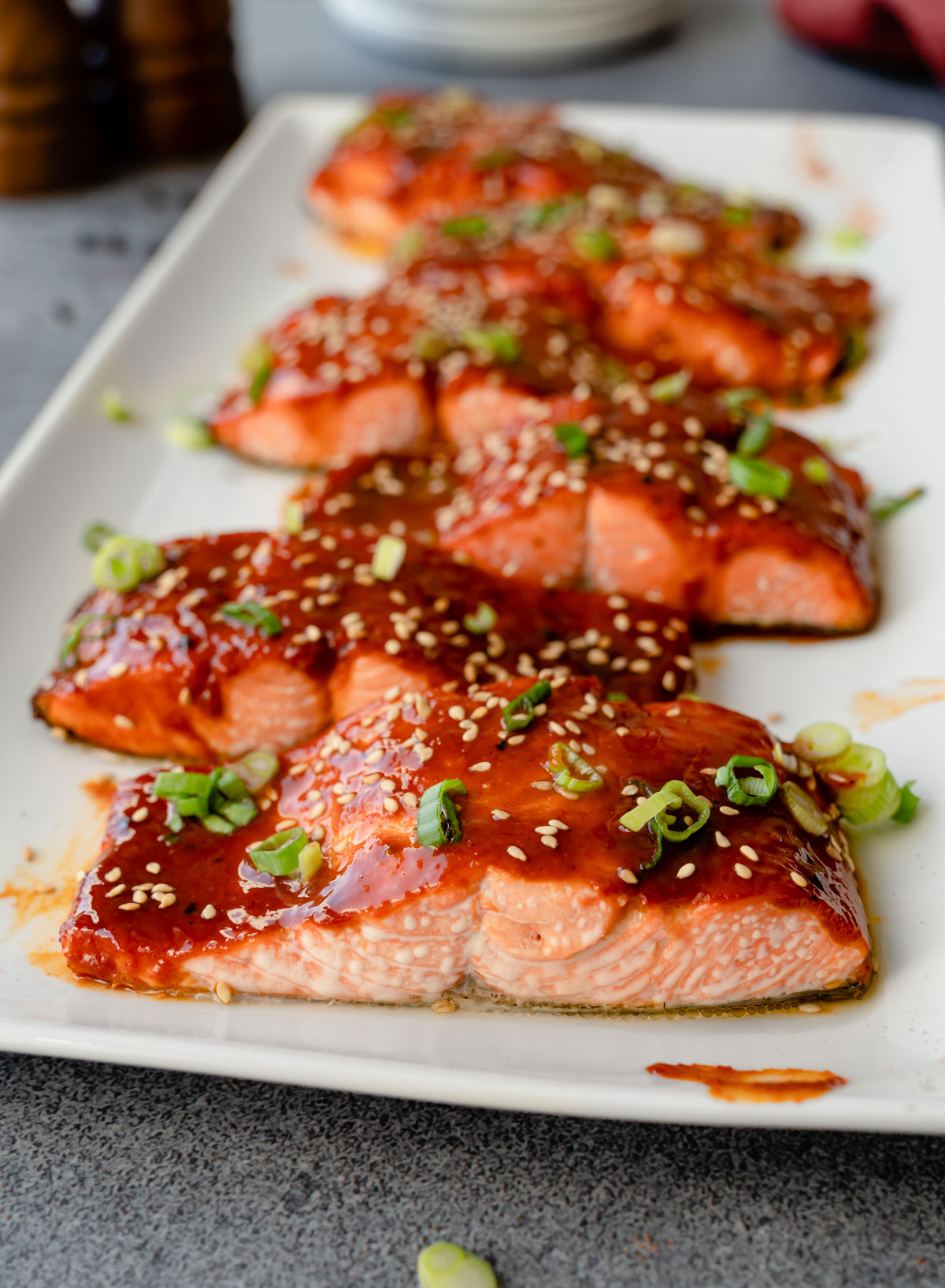 Close up of gochujang salmon topped with sesame seeds and green onion.