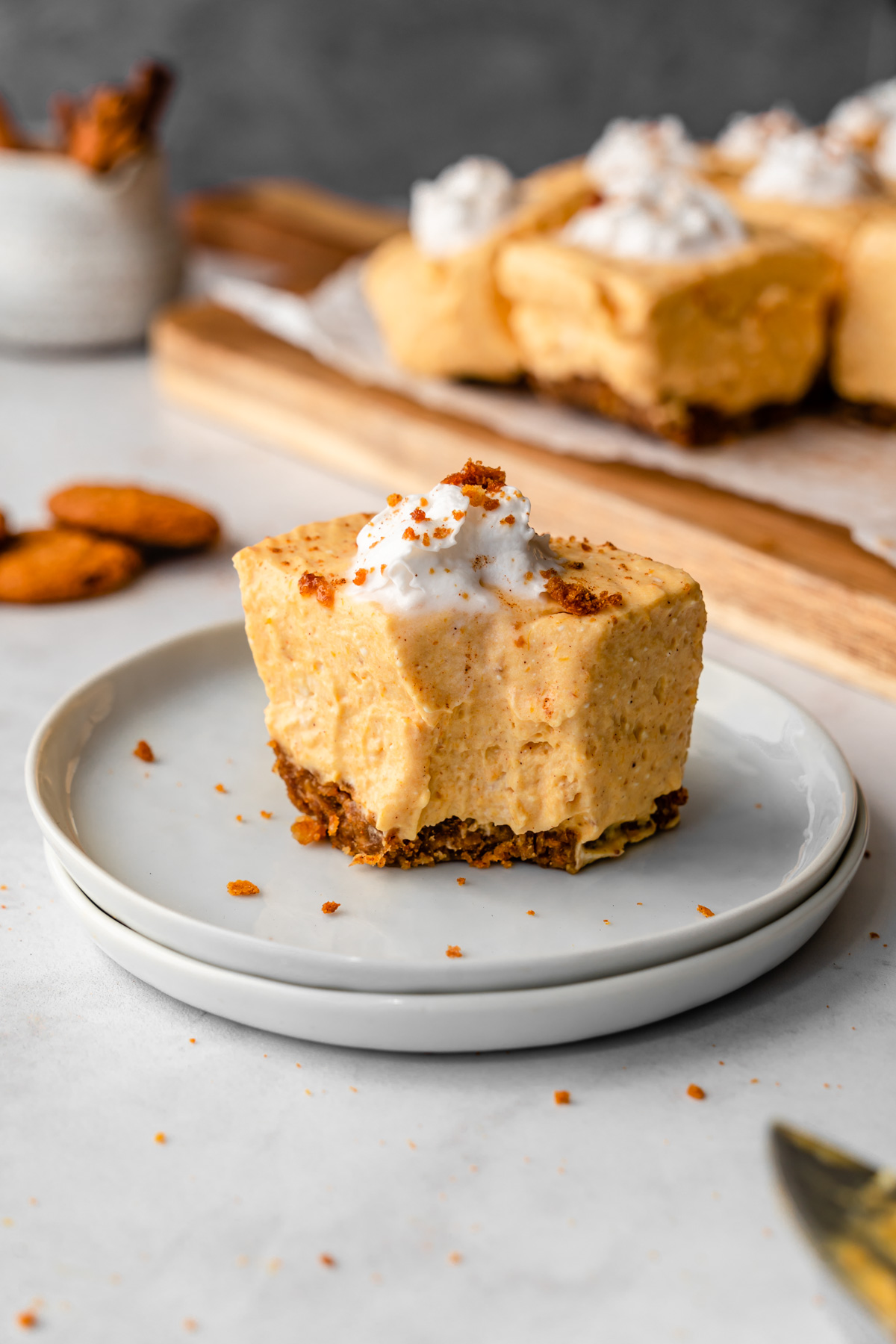 Pumpkin cheesecake bar on two plates with a bite in it.
