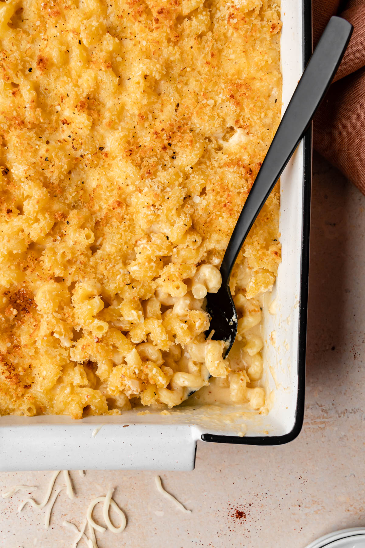 A casserole of Cavatappi Mac and Cheese with a black serving spoon.
