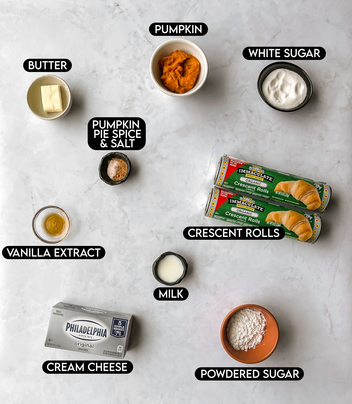 Labled ingredients for pumpkin cream cheese crescent rolls: butter, pumpkin, white sugar, pumpkin pie spice, salt, vanilla extract, crescent rolls, milk, cream cheese, and powdered sugar.