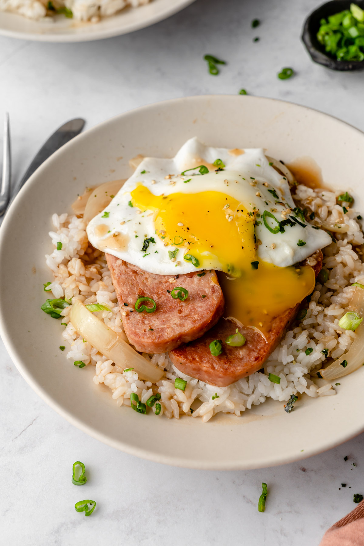 A burst fried egg on top of Spam, rice, and gravy for Spam Loco Moco.