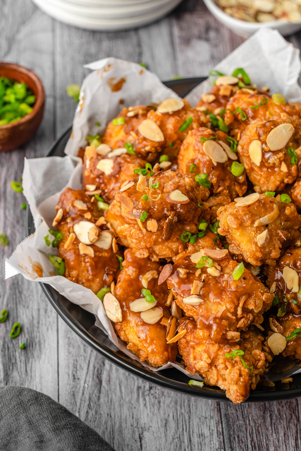 Close up of Crispy Almond Chicken Breast covered in sliced almonds, sauce, and green onion.